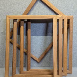 May include: Set of four unfinished wooden picture frames, stacked on top of each other. The frames are all the same size and have a simple, rectangular shape.