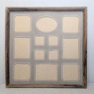 May include: A multi-opening picture frame with a brown, textured wooden frame. The frame has openings of various sizes and shapes, including rectangles and an oval. The background is a neutral gray color, and the openings have a white border.