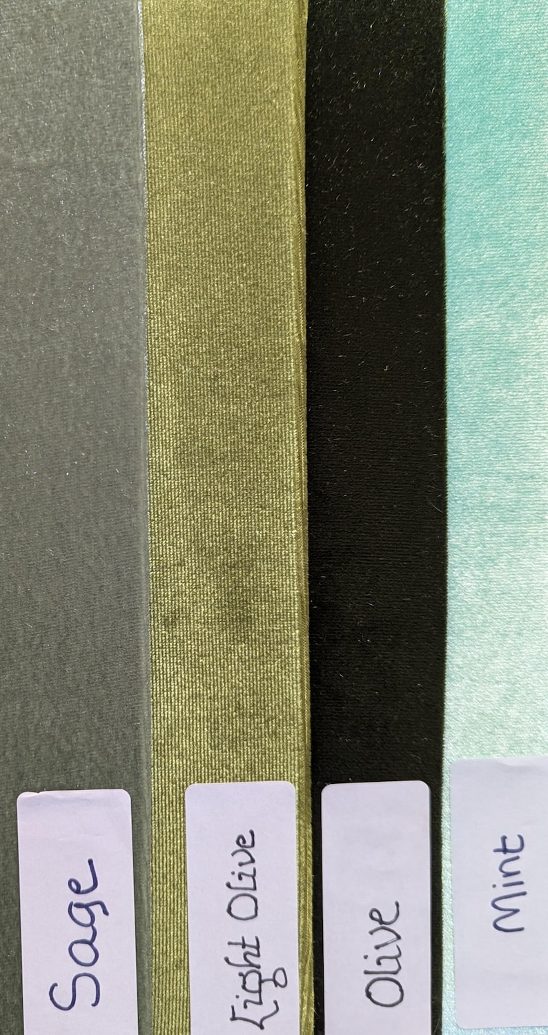 May include: Four vertical strips of fabric with a velvet-like texture in sage, light olive, black, and mint green. Each strip features a white rectangular label at the bottom with the handwritten text Sage, Light Olive, Olive, and Mint respectively.