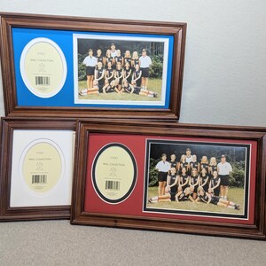 May include: Three wooden picture frames with team photos and oval mat openings. One frame has a blue mat, another a white mat, and the third a red mat. The frames are a dark brown colour.