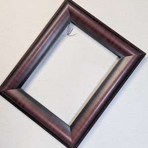 May include: A rectangular picture frame with a dark burgundy finish. The frame has a beveled edge and a metal hook for hanging. The frame is empty, ready to display a photo or artwork.