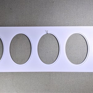 May include: White card stock with five oval cutouts. The card stock is rectangular and has a smooth, matte finish.