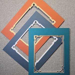 May include: Three picture frames, one on top of the other, with a gold and white trim. The top frame is orange, the middle frame is gray, and the bottom frame is teal.