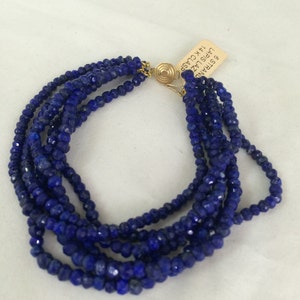 Puede incluir: Un brazalete de lapislázuli de múltiples hilos con un cierre de oro. La etiqueta dice "6 STRAND LAPIS LAZ 14K CLASP."