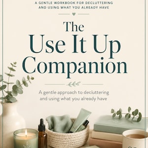 Op de afbeelding: Een stilleven met een werkboek getiteld "The Use It Up Companion" met de tekst "Een zacht werkboek voor het opruimen en gebruiken van wat je al hebt." De afbeelding bevat een brandende kaars, boeken en een gevlochten mand.