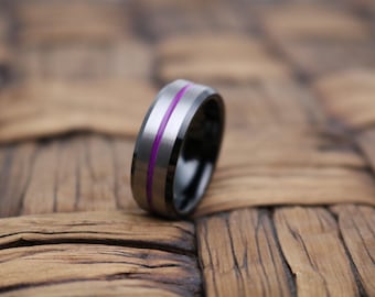 May include: A band ring featuring a brushed silver-toned outer surface with a thin, vibrant purple stripe running horizontally around the center and a polished black inner band, showcasing a sleek, modern design with beveled edges.