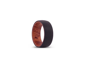 May include: A ring featuring a matte black outer band and a polished reddish-brown wood grain inner lining. The band has a smooth, rounded profile with a contrasting dark exterior and a natural, textured wood interior finish.