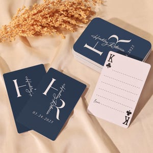 May include: Navy blue playing cards with white text and a decorative initial. The cards are personalized with the name "Hadley Rebecca" and the date "03.24.2025". A white card with a King of Clubs is also visible.