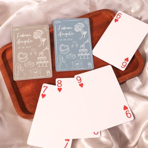 Könnte beinhalten: Ein Holztablett enthält Spielkarten und zwei personalisierte Karten. Die individuellen Karten sind hellgrau und blau, mit den Namen "Fabian Angelic" und dem Datum "07.08.2025" aufgedruckt. Die Spielkarten zeigen die Zahlen 6, 7, 8 und 9 der Herzen.