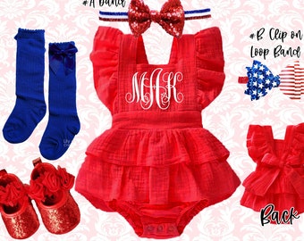 Puede incluir: Un conjunto de bebé rojo y blanco con volantes y un monograma "MHK" en la parte delantera. El conjunto se combina con zapatos rojos de purpurina, calcetines azules hasta la rodilla y una diadema con lazo rojo y blanco. La diadema tiene un lazo rojo de purpurina y una banda roja, blanca y azul.