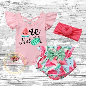 May include: A pink baby onesie with the text "One in a Melon" and a watermelon graphic. The onesie is paired with a watermelon print nappy cover with a green bow and a pink headband.