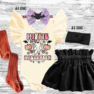 A flat lay of a children's Halloween outfit including a cream romper with a Hippie Halloween graphic, a black velvet skirt, rust-colored tights, a black headband, and a sparkly purple bow with a black bat.
