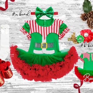 May include: A green and red elf costume with a white belt and a red tulle skirt. The costume comes with a green and red headband with a sparkly bow, white knee-high socks, and red shoes with a flower detail. The back of the costume is shown with the text "Back".