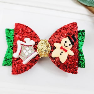May include: Red and green glitter bow with a white gingerbread house and gingerbread man decoration.