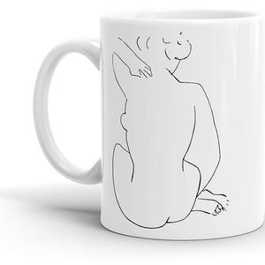 May include: White ceramic mug with a black line drawing of a person sitting with their arm raised, the drawing is in a minimalist style.
