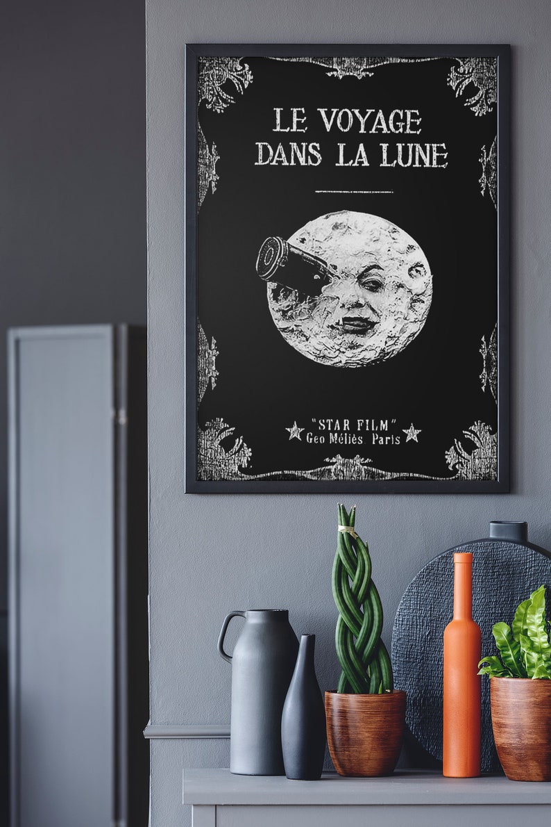 Puede incluir: Un p&oacute;ster en blanco y negro con un dise&ntilde;o vintage que presenta una luna con una cara y un telescopio. El texto en el p&oacute;ster dice "Le Voyage Dans La Lune" y "Star Film Geo M&eacute;li&egrave;s Paris".