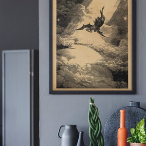 Puede incluir: Impresi&oacute;n vintage enmarcada que representa una figura alada cayendo a trav&eacute;s de las nubes, iluminada por un rayo de luz. La obra de arte est&aacute; en tonos sepia, sobre un fondo oscuro. Debajo, hay objetos decorativos.