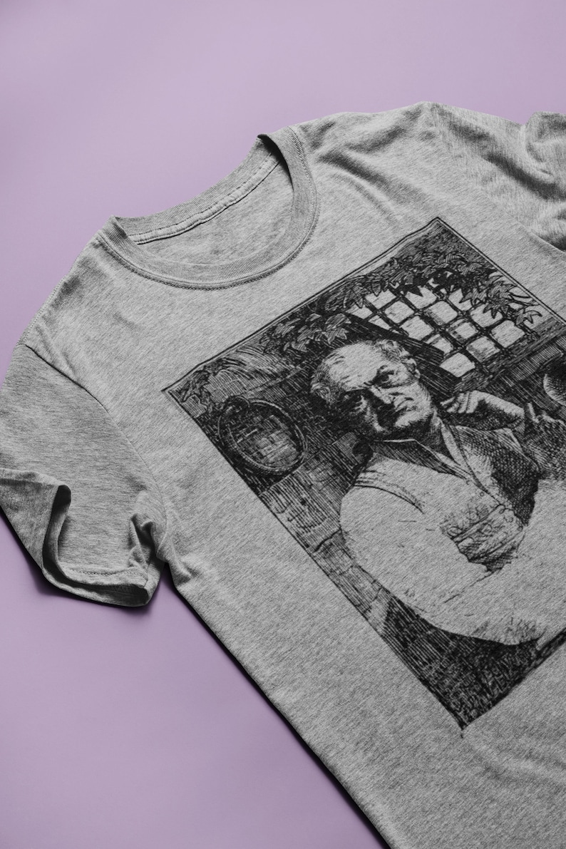 May include: A gray t-shirt with a black and white illustration of a man with a beard. The illustration is in a square frame and shows the man looking to the side.
