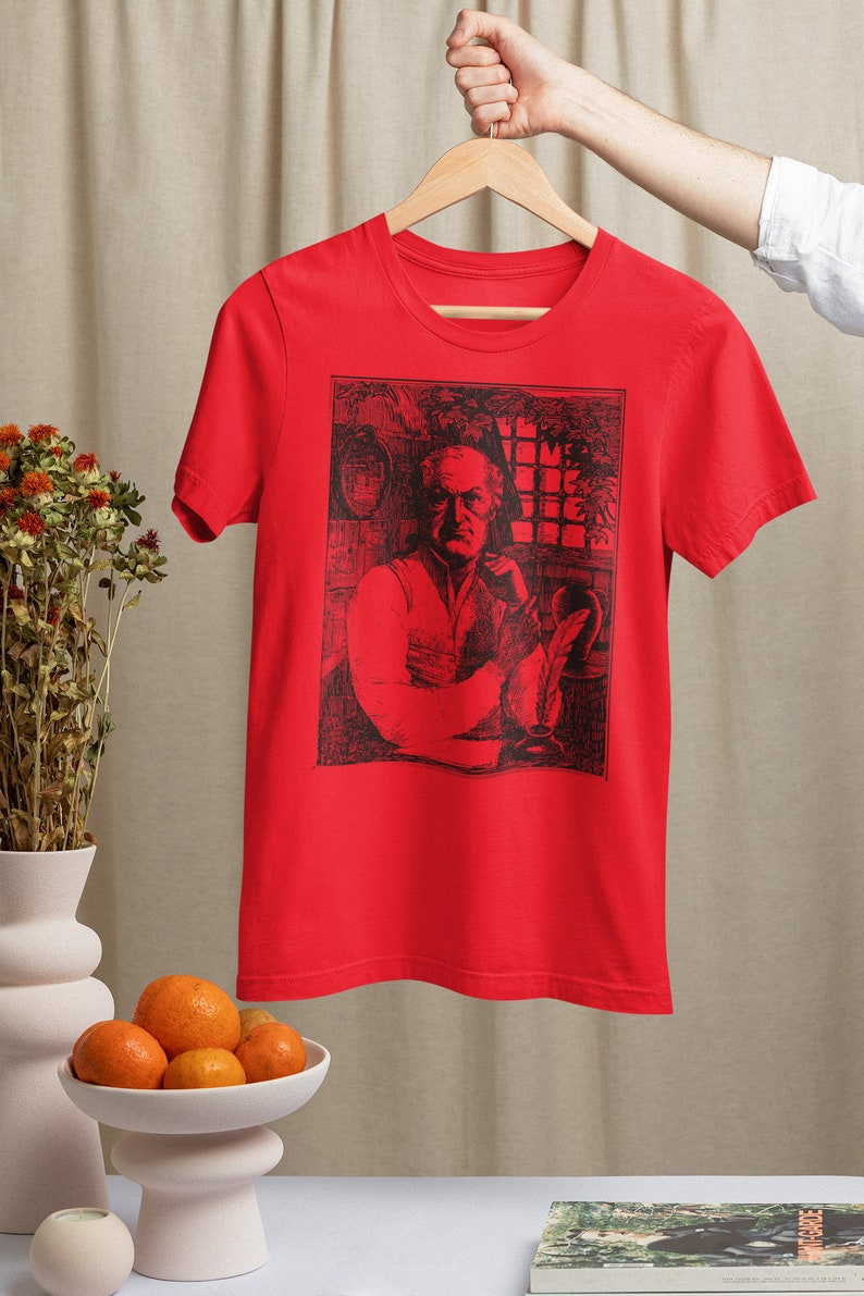 May include: Red t-shirt with a black and white illustration of a man sitting at a desk with a quill pen and inkwell. The illustration is surrounded by a black border. The text "I'll Come Back For The Rest" is visible in the illustration.