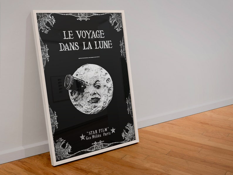 Puede incluir: Un p&oacute;ster en blanco y negro con un marco blanco. El p&oacute;ster presenta un fondo negro con texto blanco que dice "LE VOYAGE DANS LA LUNE" y una imagen blanca de la luna con una cara y un telescopio. El texto en la parte inferior dice "STAR FILM - Geo. Melies Paris."