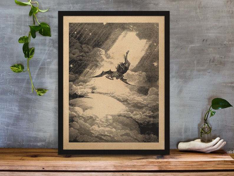 Puede incluir: Ilustraci&oacute;n en blanco y negro enmarcada que representa una figura alada cayendo por un cielo nublado. La obra de arte, sobre un fondo beige, est&aacute; enmarcada en negro y descansa sobre una superficie de madera. La imagen evoca drama y fantas&iacute;a.