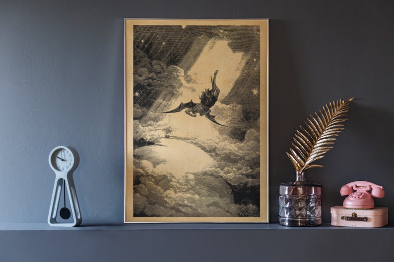Puede incluir: Impresi&oacute;n vintage enmarcada que representa una figura alada cayendo a trav&eacute;s de las nubes, iluminada por un rayo de luz. La obra de arte es en blanco y negro con un tono sepia, sobre una pared gris oscuro. Un reloj decorativo, una hoja dorada y un tel&eacute;fono rosa est&aacute;n en el estante.