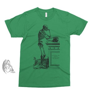 May include: A green t-shirt with a black and white illustration of a skeleton leaning on a stone pedestal. The text on the pedestal reads "VIVITE IN GENIO, ET MORIETE IN FAMA".