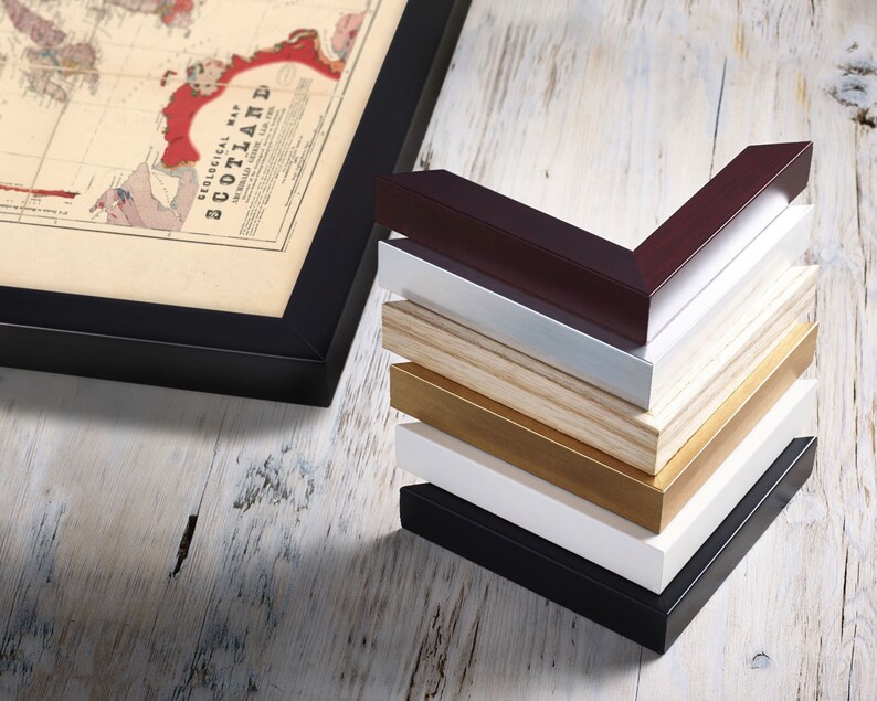 May include: A stack of different colored picture frames, including black, white, gold, wood, and burgundy. The frames are all in the same style and size, and they are arranged in a pyramid shape.