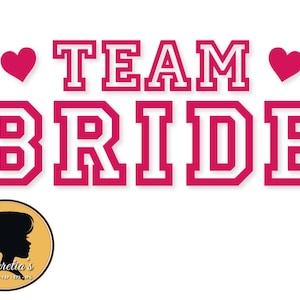 Può includere: Grafica rosa e bianca con il testo "TEAM BRIDE" in un carattere audace e a blocchi. Due cuori rosa sono su entrambi i lati del testo.