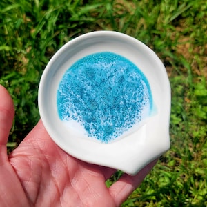 May include: White ceramic spoon rest with a teal blue and white marbled design.