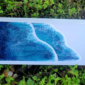 May include: A white rectangular serving tray with a blue and white resin ocean wave design. The tray is perfect for serving snacks or appetizers.