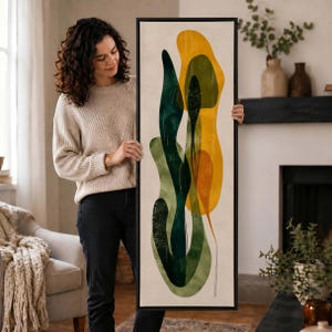 May include: A tall, rectangular framed wall art piece featuring abstract, organic shapes in shades of deep forest green, olive, and vibrant mustard yellow on a light cream background, enclosed within a thin black frame.