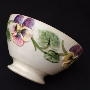 Può includere: Una tazza di ceramica bianca con un manico nero e la scritta "But First, Coffee" in nero, con un carattere a mano. La tazza è su una superficie bianca.