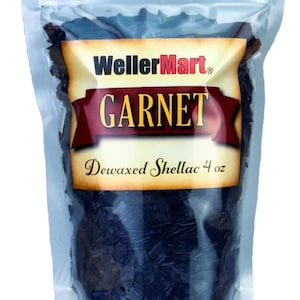 May include: A clear plastic bag filled with dark brown, dewaxed shellac flakes. The bag has a label that reads "WellerMart Garnet Dewaxed Shellac 4 oz."