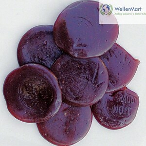 May include: A close-up of a pile of round, dark purple candy. The candy is smooth and shiny, and some of the pieces have text printed on them.
