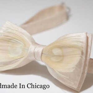 May include: A white bow tie made of feathers with a satin center. The bow tie is handmade in Chicago.