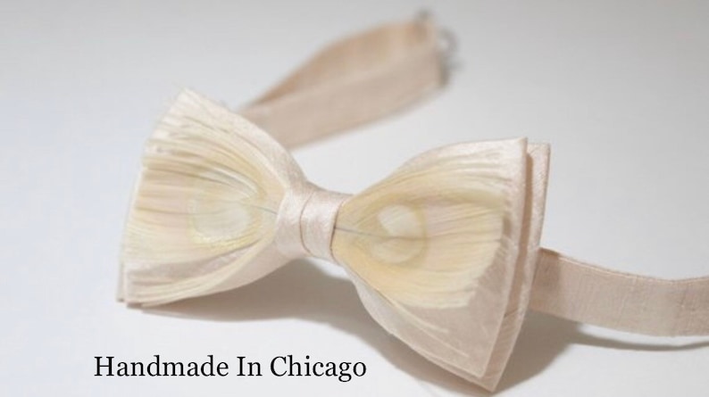 May include: A white bow tie made of feathers with a satin center. The bow tie is handmade in Chicago.