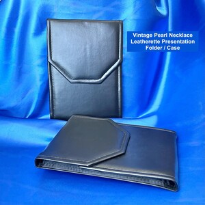 May include: Two black leatherette presentation folders or cases. The top folder is closed, and the bottom folder is open. The text on the image reads: "Vintage Pearl Necklace Leatherette Presentation Folder / Case."