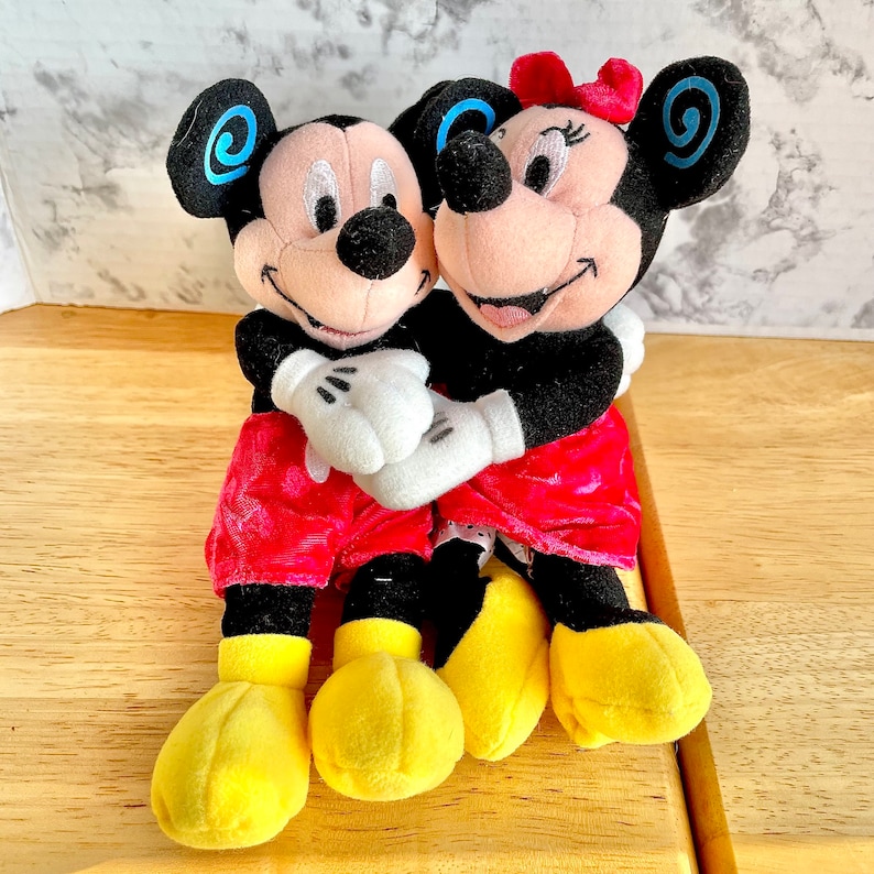 Mickey Minnie Mouse Hugging plushie doll, holding hands, blue swirls  on ears, smiling.