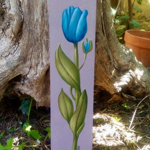 Puede incluir: Una pintura de un tulipán azul con hojas verdes sobre un fondo morado. La pintura está firmada "Z. Yosavitz" en la esquina inferior derecha.