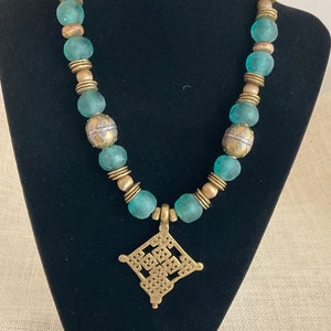 Arican Blue Glass Beads accented by Brass forcal, brass spacer beads accented by an antique pendant
