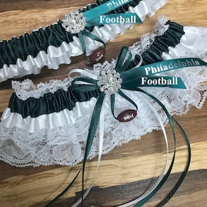 May include: Two green and white garters with a football charm and a ribbon that says "Philadelphia Football".