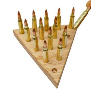 May include: A wooden triangle game board with 15 brass-colored bullet-shaped pieces. The board has a hole in the center and a small hole on each side. One bullet is being removed from the board with a hand.