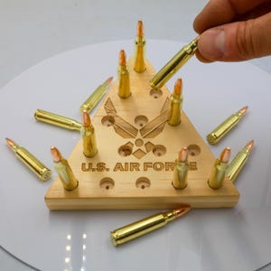 May include: A wooden triangular display stand with the text "U.S. AIR FORCE" and the Air Force emblem. The stand holds several gold-colored bullets, with additional bullets scattered around it.