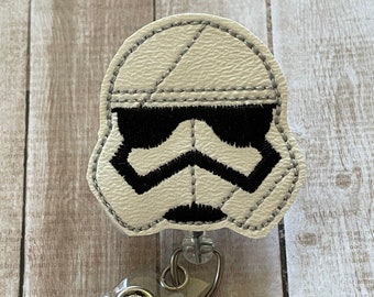 May include: White and black embroidered Stormtrooper character badge reel with a clear plastic badge holder and a silver clip.