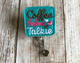 May include: Teal blue square badge holder with the text "Coffee before Talkie" in brown, pink, and white embroidery. The badge holder is attached to a retractable badge reel.