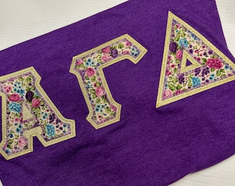Camisa con letras de estilo suave Gildan de la Hermandad Griega en Heather Orchid con letras griegas multiflorales y doradas metálicas