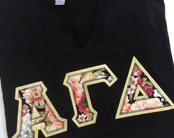 Camisa con cuello en V y letras griegas de hermandad en negro con letras florales