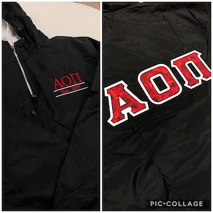 May include: Black windbreaker jacket with a red and white embroidered logo that says "AOPII Est. 1897" on the left side and a large red and white "AOPII" logo with a red rose pattern on the right side.