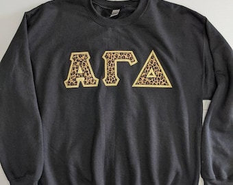 Sudadera con letras griegas de la hermandad en color negro y tela con estampado de guepardo